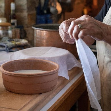 Griechische Großmutter bei der Zubereitung von traditionellem griechischen Joghurt in der Küche